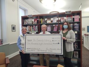 Friends member Cathy Weidman, Library Board President Ken Hotopp, and Youth Services Coordinator Courtney Little pose with an oversized donation check presented by the Friends to support the library's Battle of the Books programs.