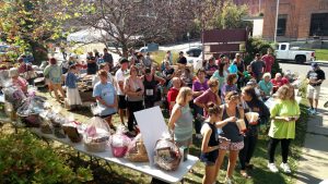 a crowd gathered on the front lawn of the library awaiting the announcement of basket raffle winners