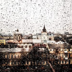 a view of an old cityscape seen through a window with scattered raindrops